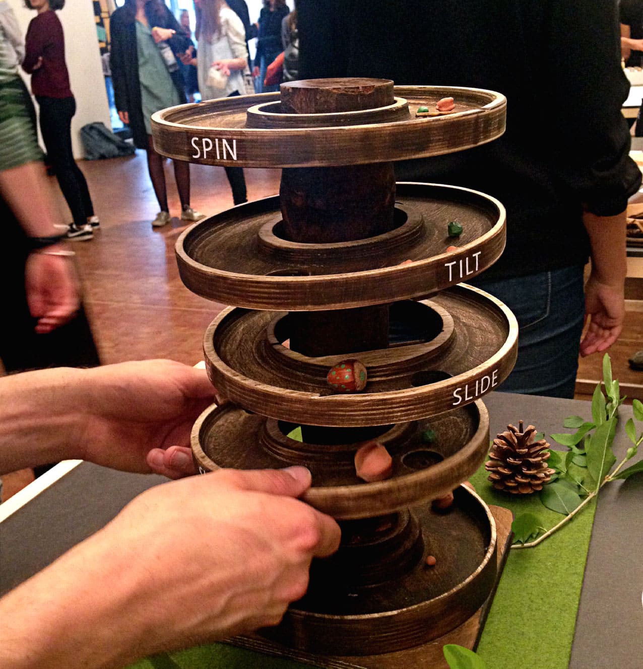 Two hands holding the board game tower at one of the sections. Some hazelnuts lie on top of the layers.